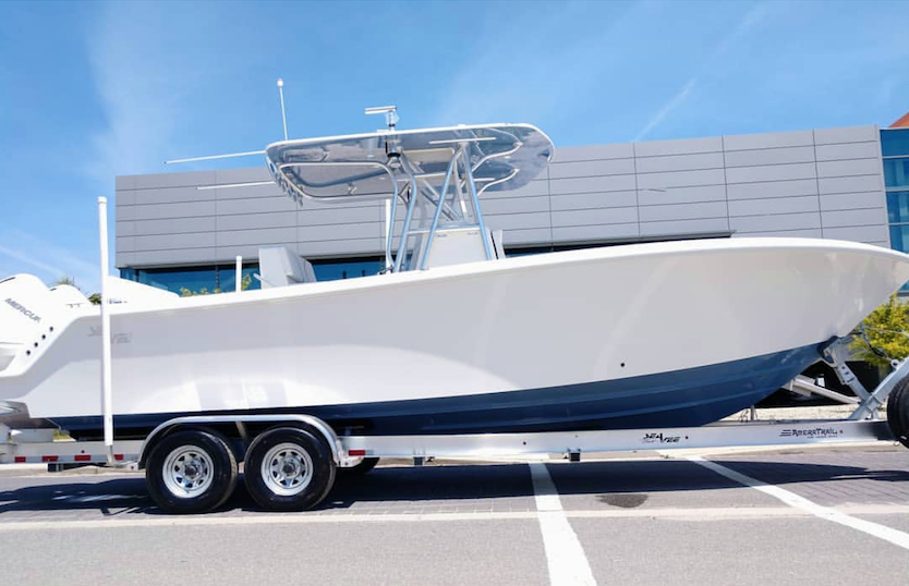 White boat with navy blue hull in front of large building White boat with navy blue hull in front of large building